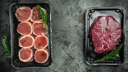 Raw fresh marbled meat Steak filet mignon. medallion steaks wrapped in bacon on dark concrete background. Meat products in packed