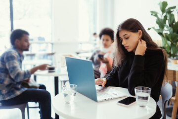 Portrait of female student using net-book while sitting in cafe