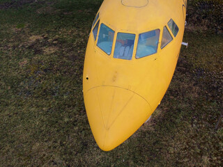 aerial view from drone of a small old jet yellow passenger plane cockpit standing in a field