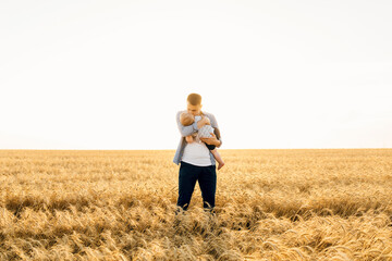 Happy family on a summer walk, mother, father and child walk in the wheat