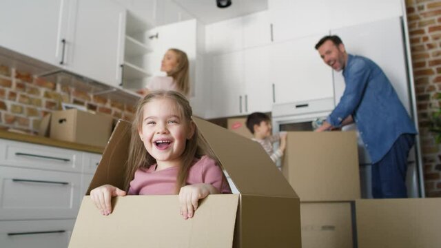 Playful girl jumps out of cardboard while moving house. Shot with RED helium camera in 8K.