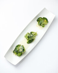 Blanched broccoli with sauce, mini portion. Vegetables on white plate. Diet food, minimum calories. Object isolated on white background. 