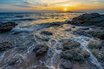 Sea waves crashed against rocks in the sunset at Pattaya Thailand.