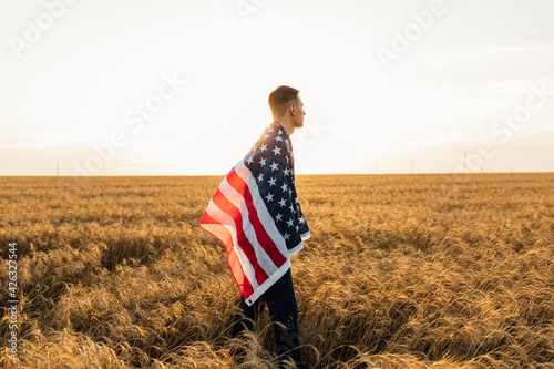 young man with America USA flag at sunset outdoors on field