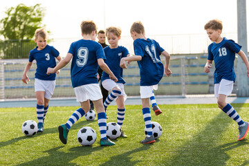 Group of Soccer Team Players on Training Session with Coach. Happy Kids Kicking Football Balls on Summer Training Camp