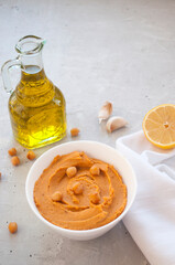 A bowl of delicious hummus with olive oil, garlic and paprika on a grey background.