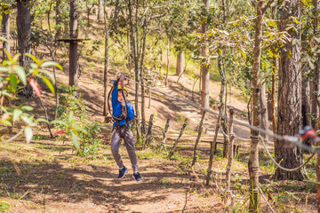 Obraz premium Happy child in a helmet, healthy teenager school boy enjoying activity in a climbing adventure park on a summer day