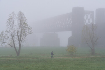 Naklejka na ściany i meble Spaziergänger im Nebel vor der Silhouette der Urmitzer Eisenbahnbrücke