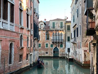 Tourist visiting Venice on a gondola on a small canal street in Venice, Italy
