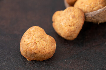 Homemade coconut biscuits from coconut paste, heart crumbly coconut cookies in half coconut shell on black stone board. Horizontal, close up