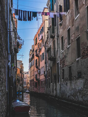 Picturesque little canal street in Venice with a boat and clothes drying in the sun