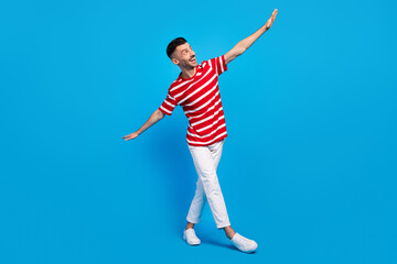 Fototapeta premium Full body photo of funky happy cheerful man look empty space hands wings isolated on blue color background