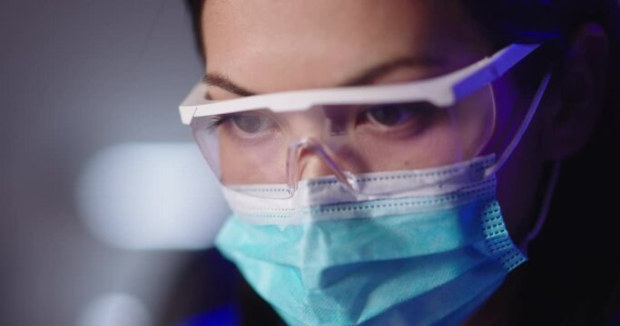 Close up shot of face of a doctor or scientist at work, wearing protection mask and goggles. Focused worker during pandemic time 4k footage - Powered by Adobe