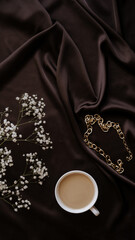 coffee wih milk, gold chain, gypsophila on brown atlas background