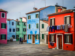 Fototapeta na wymiar Person walking in the typical and very colorful streets of Burano. We see laundry being dried outside