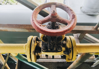 Industrial metal old round valve with a pipe for the supply of gas, ammonia, nitric acid, with bolts in grease close-up.