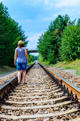 Lonely young woman on a railway in forest