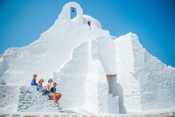 Family vacation in Europe. Parents and kids at street of typical greek traditional village with...