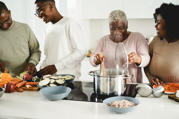 Happy black family cooking vegan food inside kitchen at home - Focus on mother face - Powered by Adobe