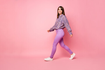 Full body profile portrait of adorable lady walking beaming smile look camera isolated on pink color background