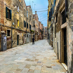 Obraz premium Venice, Italy, February 19, 2021 - Unrecognizable people talking at phone with a protective mask and walking alone during the crisis COVID-19
