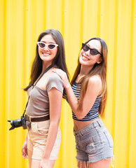 Portrait of two beautiful Asian women wearing summer fashion suits having fun together in an amusement park.