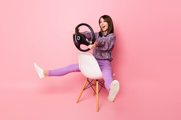 Full length photo portrait of crazy girl with steering wheel sitting on white chair isolated on...