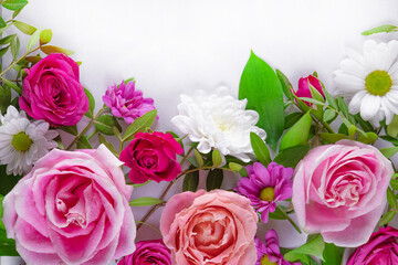 Fototapeta premium Beautiful summer flowers on the white background with empty space for text. Pink roses and white daisies top view