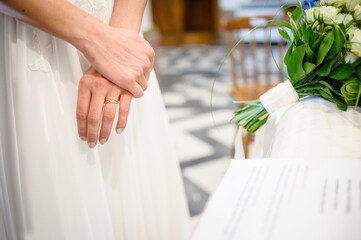 close up on the hands of a bride during wedding, with wedding ring on her finger. Celebration of marriage in a church.