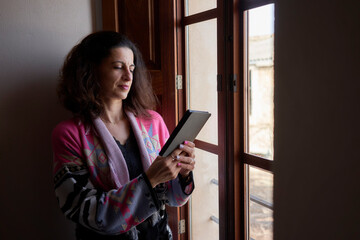 Mujer leyendo libro electrónico en ventana