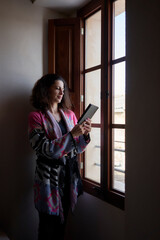 Fototapeta na wymiar Mujer leyendo libro electrónico en ventana