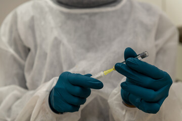 Arzt befüllt Spritze mit dem Impfstoff gegen Corona, Covid-19, Hände in den Gummihandschuhen und...