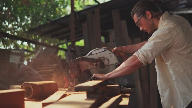 A carpenter cutting wooden plank with electric buzzsaw. Woodworking and carpentry. Craftsmanship.	
