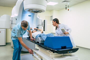 Cancer treatment in a modern medical private clinic or hospital with a linear accelerator. Professional doctors team working while the woman is undergoing radiation therapy for cancer - obrazy, fototapety, plakaty
