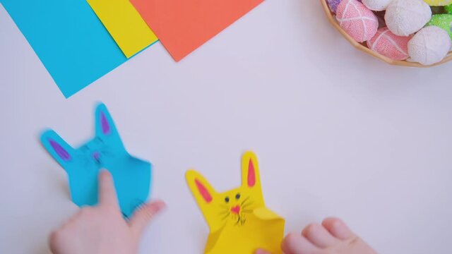 Kids fingers holding easter Craft colorful paper bunnies and jumping.