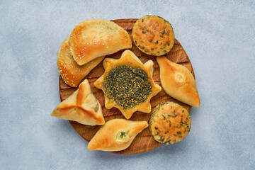 Pastries, fatayer or samosa, manaqeesh with zaatar and cheese . Assorted pasties  with spinach and potato on wooden board. Top view