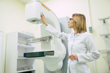 Cute professional woman doctor is working with modern Mammography X-Ray System Machine in a...