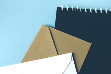 White and beige envelopes and notebook with black paper on blue background. Blank template