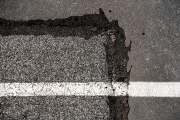 deteriorated asphalt floor texture with a line of white paint

