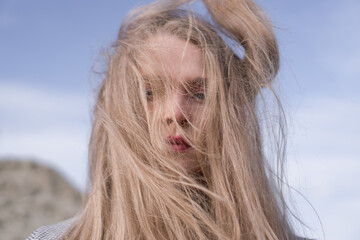 Beauty portrait of a young blond girl in a vintage dress. She is posing on a sandy landscape.