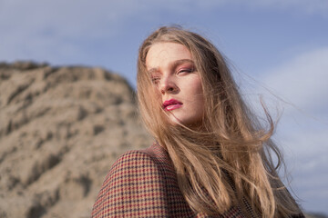 Fototapeta premium Beauty portrait of a young blond girl in a vintage dress. She is posing on a sandy landscape.