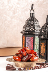 Muslim holiday of the holy month of Ramadan Kareem. Beautiful background with shining lantern, dried dates, prayer beads and quran book
