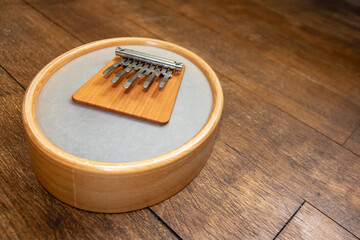 Sansula or kalimba instrument with membrane on a wooden floor background with copy space. Thumb...