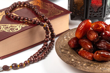 Muslim holiday of the holy month of Ramadan Kareem. Beautiful background with shining lantern, dried dates, prayer beads and quran book