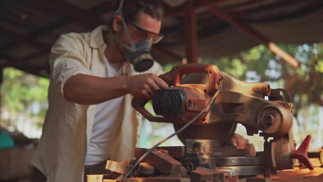 A carpenter cutting wooden plank with electric buzzsaw. Woodworking and carpentry. Craftsmanship.	
