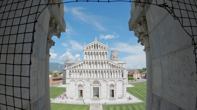 wide and high angle view of the front facade of the cathedral of the Archdiocese of Pisa dedicated to Santa Maria Assunta in Piazza dei Miracoli. Leaning Tower in background.