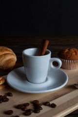 Aromatic coffee with cinnamon sticks, coffee beans and a donut on a wooden background. Coffee break.