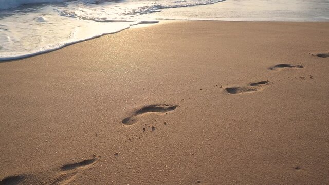 huellas en la arena y&eacute;ndose con el mar 