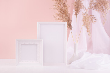Mock up for display portfolio, design, text or pictures in two blank photo frame in soft light interior with silk curtain, fluffy reeds on white wood table, pink wall.