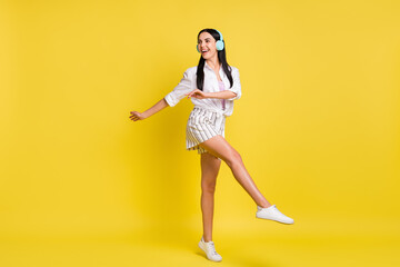 Fototapeta na wymiar Full size photo of young beautiful pretty smiling girl dancing listen music in earphones isolated on yellow color background